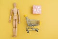 Shopping cart with wooden man mannequin shopping bags. Buying gifts for online shopping, supermarket concept. Copy space Royalty Free Stock Photo
