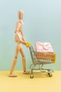 Shopping cart with wooden man mannequin shopping bags. Buying gifts for online shopping, supermarket concept. Vertical Royalty Free Stock Photo