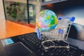 Shopping cart with world globe balloon map for retail business on notebook. Image use for online and offline shopping Royalty Free Stock Photo