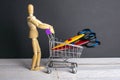 Shopping concept. Figure of a wooden man with a basket filled with stationery scissors Royalty Free Stock Photo