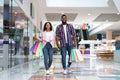 Shopping Concept. Happy Black Couple Walking In Mall Carrying Colorful Shopper Bags Royalty Free Stock Photo