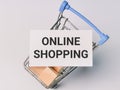 Phrase ONLINE SHOPPING on white card with trolley full of wooden cubes.