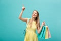 Shopping Concept: Portrait of an excited beautiful girl wearing yellow dress holding shopping bags isolated over blue Royalty Free Stock Photo