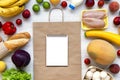 Shopping concept. Set of different groceries with paper bag and blank notebook on white wooden surface, top view. Cooking food bac Royalty Free Stock Photo