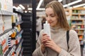 Shopping cosmetics - woman smelling bottle of shampoo in store Royalty Free Stock Photo