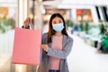 Shopping during covid. Young Asian female client in face mask holding gift bags with mockup for brand logo at city mall