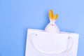 Shopping for Easter. White paper shopping bag with white bunny on blue background. Concept Easter gifts, surprise. Royalty Free Stock Photo