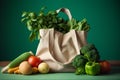 Shopping fabric tote bag with groceries and fresh green herbs and vegetables on green background