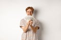 Shopping and finance concept. Lucky redhead guy winning, showing prize money and smiling happy, standing in glasses and