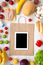 Shopping groceries concept. Food bag and various healthy food with tablet on white wooden table. Cooking food background. Flat lay Royalty Free Stock Photo