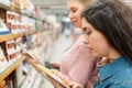 Shopping at the grocery store. Two young women choose products in the store and reading information at the product. In the Royalty Free Stock Photo