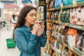 Shopping at the grocery store. A young brunette woman chooses a product by sniffing the fragrance through the packaging. Close up