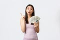 Shopping, holidays and people emotions concept. Attractive korean woman in evening dress, showing money and raise index