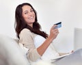 Shopping is just a click away. Portrait of an attractive woman holding a credit card while using a laptop. Royalty Free Stock Photo