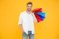 Shopping Makes Him Feel Better. Handsome Man Smiling With Shopping Bags On Yellow Background. Happy Shopper Holding
