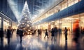 A shopping mall decorated for christmas with a large illuminated Christmas tree and busy shoppers