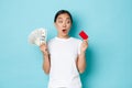 Shopping, money and finance concept. Amazed beautiful asian girl in white t-shirt gasping astonished and looking at