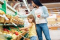 Daily Shopping. Mother and daughter in the supermarket choosing vegetables concentrated Royalty Free Stock Photo
