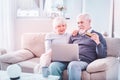 Bearded elderly man holding bank card shopping online with wife