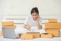 An Asian woman is using a tablet and a computer to happily find and choose products in her bed at home.