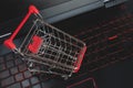 Shopping online concept - shopping cart on the black keyboard. Red mettal trolley on a laptop keyboard. Shopping service on the