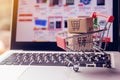 Shopping online concept - Parcel or Paper cartons with a shopping cart logo in a trolley on a laptop keyboard. Shopping service on