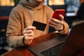 Shopping and online payment using cellphone and credit card. Man sitting in a cafe wearing casual clothes buys goods and pays via Royalty Free Stock Photo