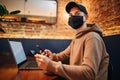 Shopping and online payment using cellphone, laptop and credit card. Man wearing mask during pandemic quarantine sits in a cafe Royalty Free Stock Photo