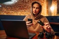 Shopping and online payment using laptop and credit card. Man sitting in a cafe wearing casual clothes buys goods and pays via Royalty Free Stock Photo