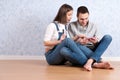 Shopping online together. Beautiful young loving couple shopping online while sitting on the floor together