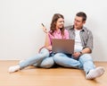 Shopping online together. Beautiful young loving couple shopping online while sitting on the floore together