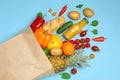 Shopping paper bag with different groceries on blue background, flat lay Royalty Free Stock Photo