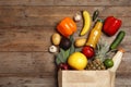 Shopping paper bag with different groceries on wooden background. Space for text Royalty Free Stock Photo