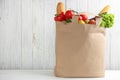 Shopping paper bag with different  on table against white wooden background. Space for text Royalty Free Stock Photo