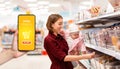 Shopping. Portrait of a young woman smiling and holding a baby in her arms and choosing candy. Indoor. The concept of online Royalty Free Stock Photo