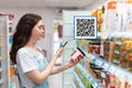 Shopping. A pretty young woman scans the composition of the body cream. Modern technology in everyday life