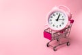 Shopping, purchases, supermarket, sale, mall concept. A metal supermarket trolley in miniature with alarm clock inside. Grocery
