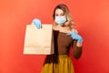 Shopping safe, stay at home. Woman in protective mask and gloves pointing paper bag with food Royalty Free Stock Photo