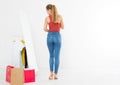 Shopping sale concept. Blonde girl in jeans and t shirt. Young woman in good body shape looking at mirror and lose weight. Royalty Free Stock Photo