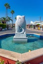 Shopping street in Ayia Napa in Cyprus with roundabout with fish figure monument.