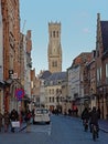 Shopping street in the historic center of Bruges, with tower of the belfry in the distance Royalty Free Stock Photo