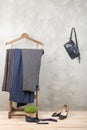 Shopping and style concept - clothes rack with trendy striped pants, blue bag and shoes on wooden floor and grey concrete Royalty Free Stock Photo