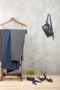 Shopping and style concept - clothes rack with trendy striped pants, blue bag and shoes on wooden floor and grey concrete Royalty Free Stock Photo