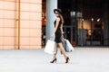 Shopping trip. black Friday. happy attractive girl in an elegant black dress, hat and sunglasses, with shopping bags, smiles as Royalty Free Stock Photo