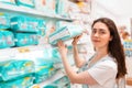 Shopping trip. Young beautiful woman pulls a pack of diapers from the top shelf. Close up Royalty Free Stock Photo