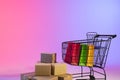 Shopping trolley with bags, boxes and copy space over neon purple background