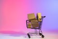 Shopping trolley with boxes and copy space over neon purple background