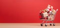 A shopping trolley carrying gifts against a red backdrop