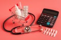 Shopping trolley cart filled pills, bottle and syringe, calculator on pink background, selective focus Royalty Free Stock Photo