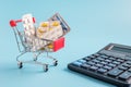 Shopping trolley cart filled pills and tablets and calculatoron blue background